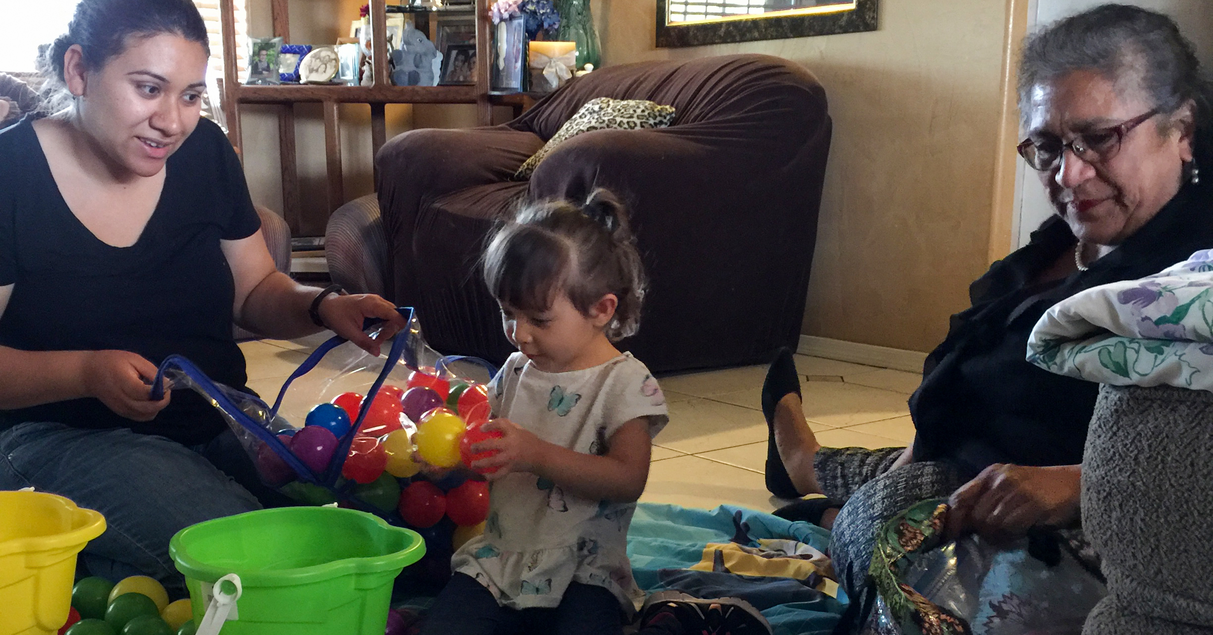 mom, daughter and parent educator sitting on floor playing with plastic balls.