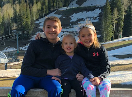 Three children sitting together outdoors.