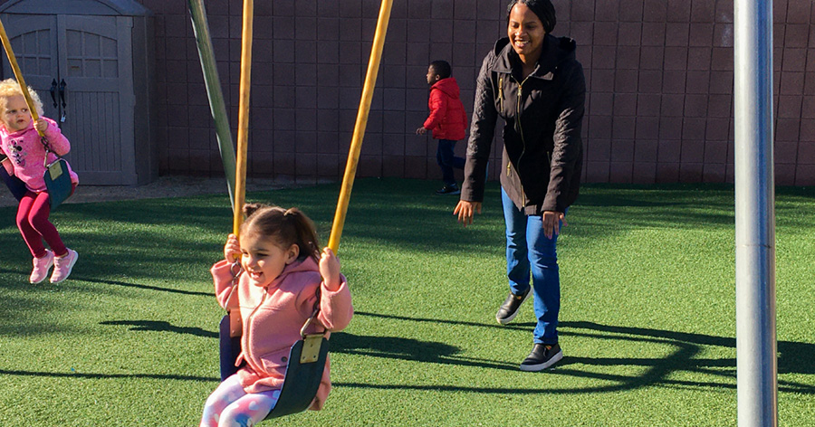 teacher pushing little girl on swing