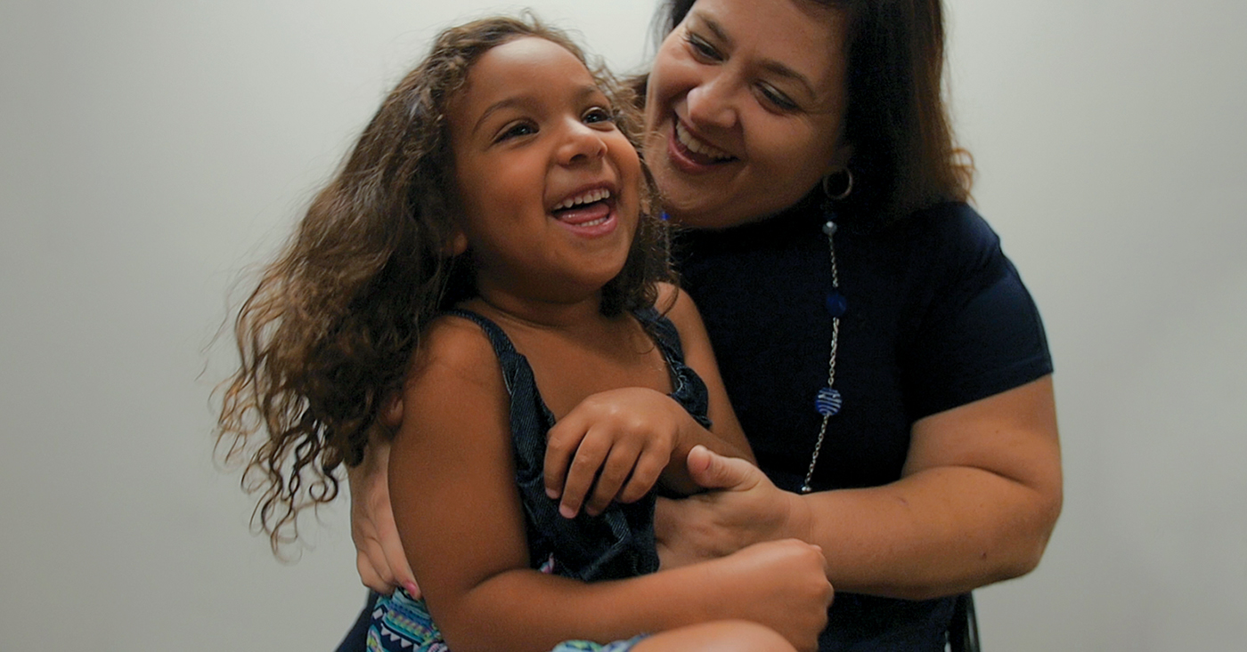 Mother hugging daughter, both smiling