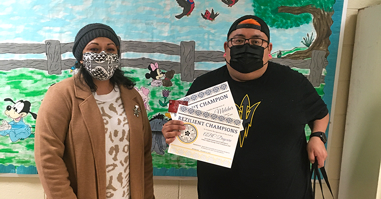 Jandi and Cedric from ABC Daycare, wearing masks holding an award