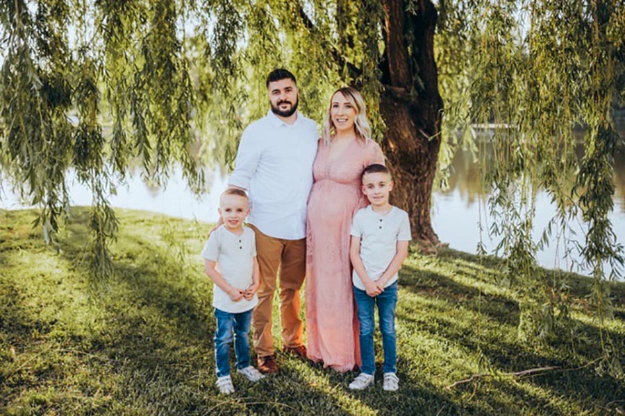 Gage family photo, dad, mom, two sons standing outside near a tree