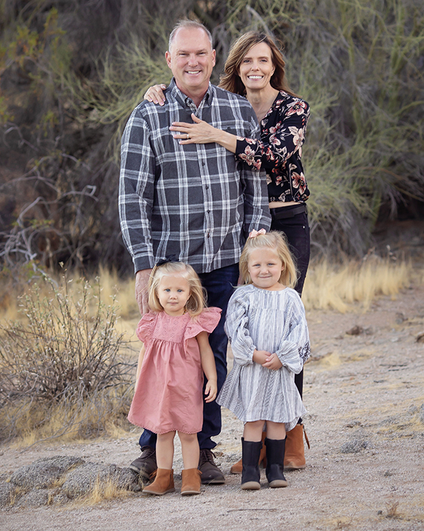 Husband and wife along with their two toddler daughters posing for family photo in the desert