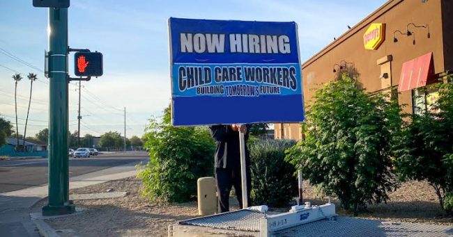 sign-spinner on corner advertising employment for child care workers