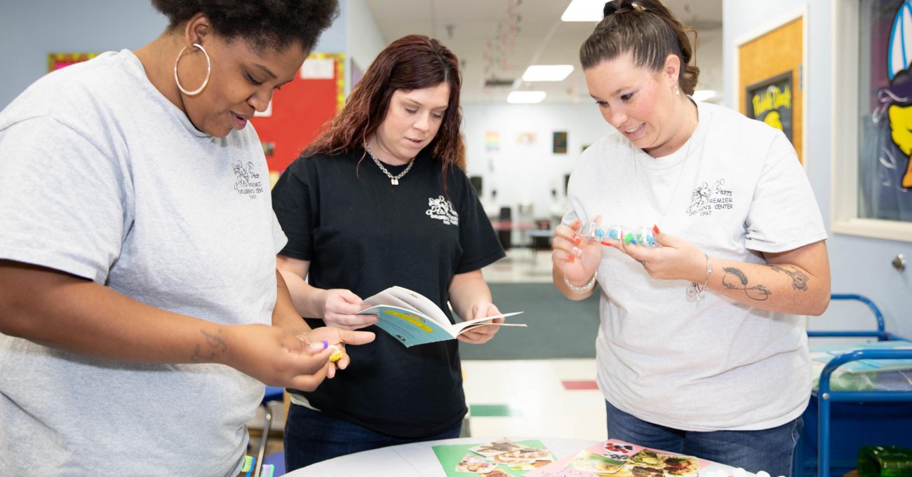 Three child care teachers training on early literacy, each holding children's books.