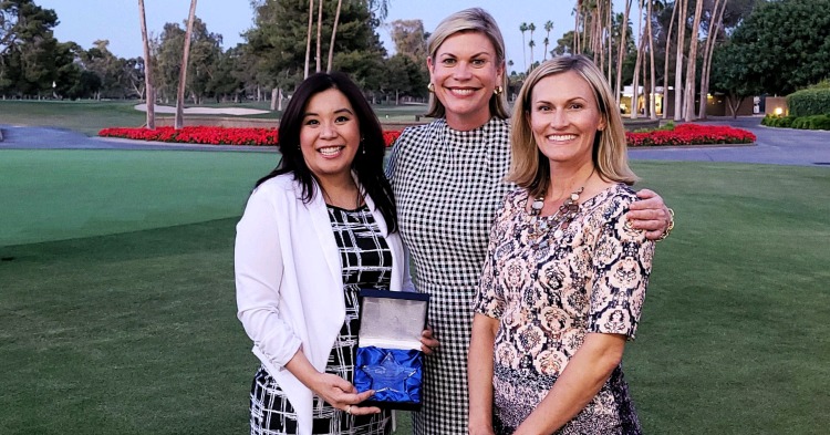 three women stand outside of Phoenix resort, holding an award