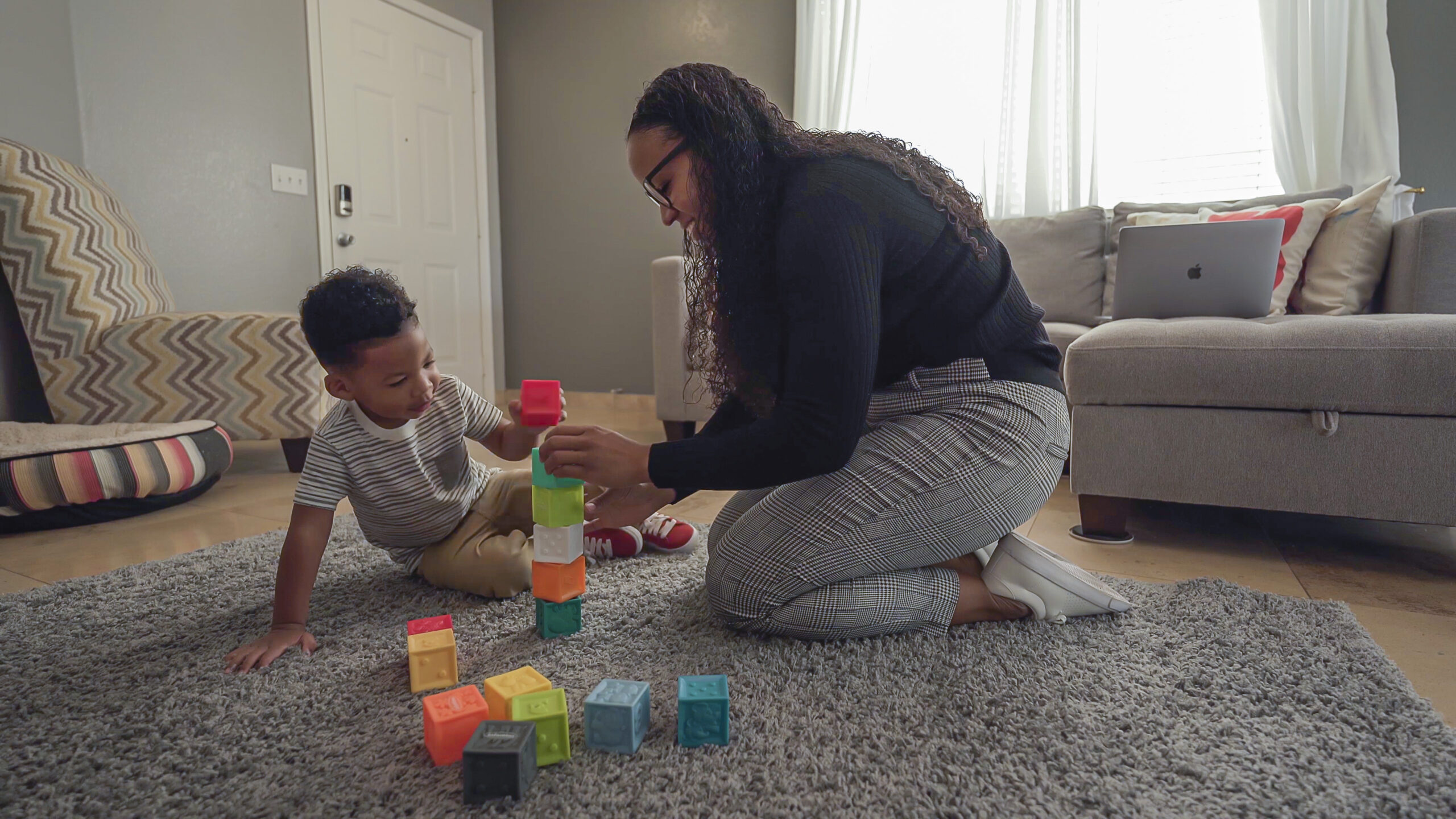 Mom kneeling down on floor playing blocks with son, children learn through play