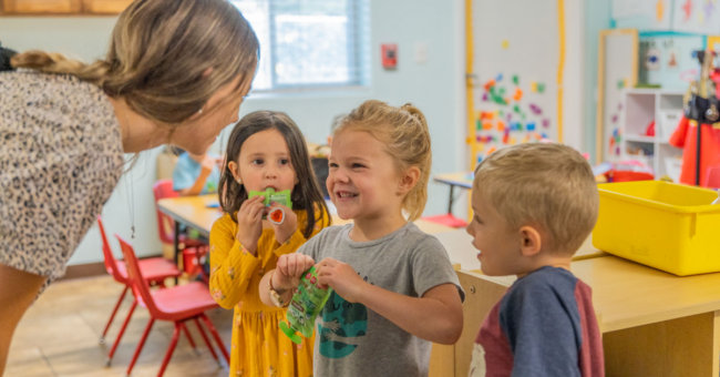 Quality First Arizona preschool in Flagstaff, teacher bending down to interact with students