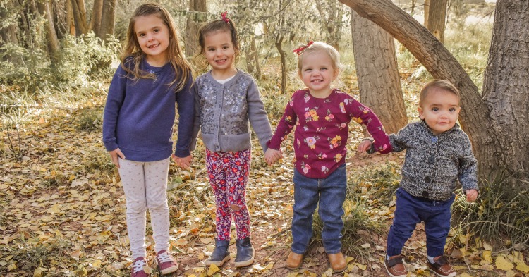 Four siblings holding hands in forest, Arizona Children's Association