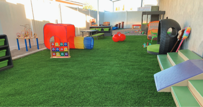 Backyard playground area with turf and playground equipment.