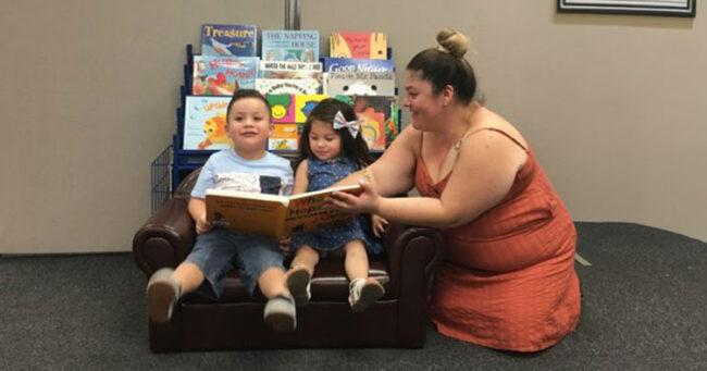 Mom with two children reading a book at family resource center.