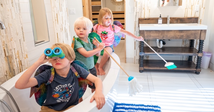 Three young children playing make believe pirates in a bathtub