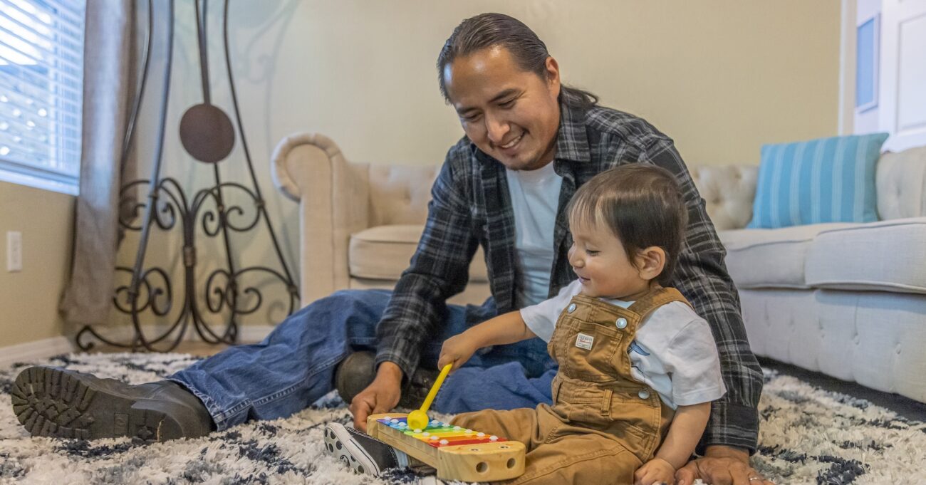 Father playing with a musical instrument next boy toddler