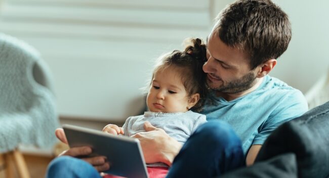 Happy father and his little girl using touchpad while relaxing at home