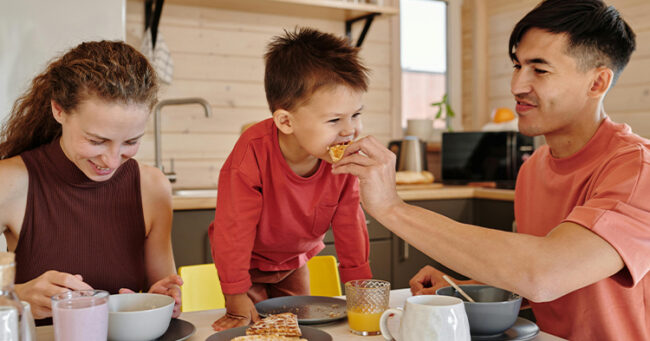 Healthy family table mealtime with parents and child eating breakfast together and building positive nutrition habits