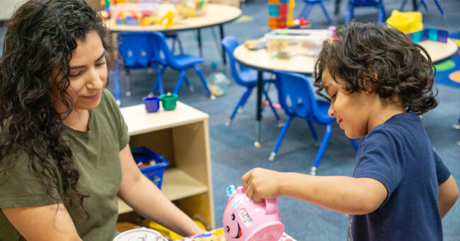 Mother with a green shirt playing with her son in blue shirt at a family resource center.