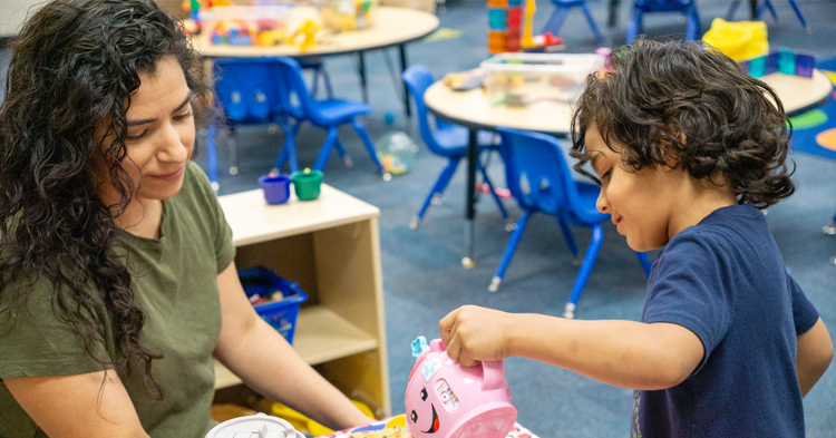 Mother with a green shirt playing with her son in blue shirt at a family resource center.
