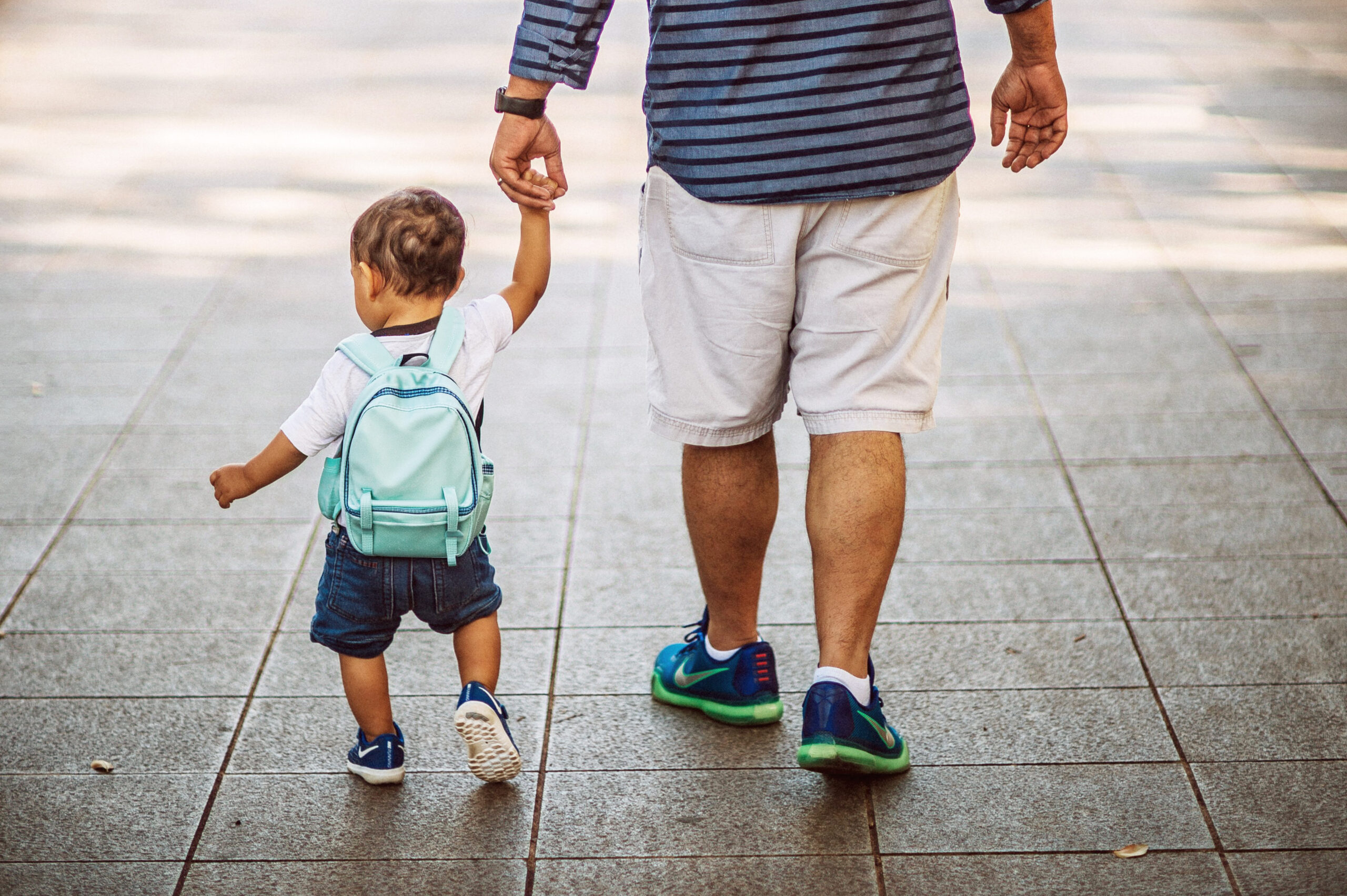 Father holding toddler's hand as they walk